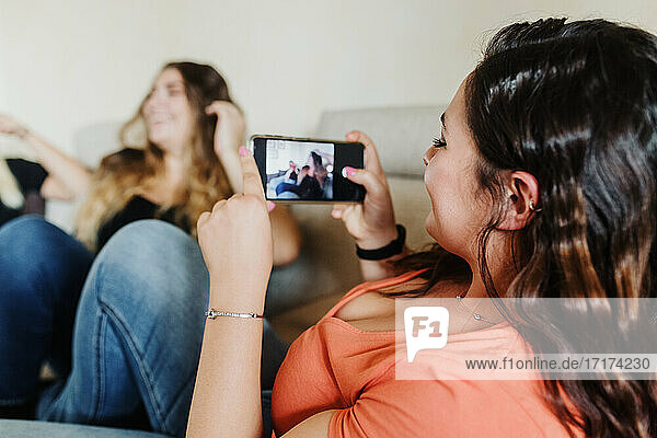 Junge Frau fotografiert Freunde mit Telefon