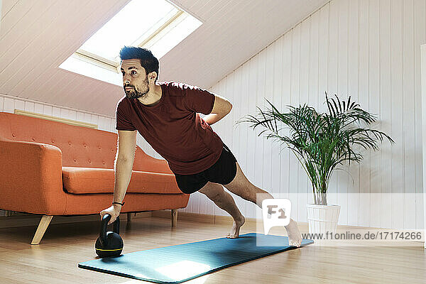 Man exercising at home  push up with kettlebell