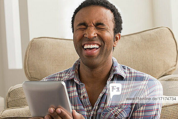 Junger Mann mit elektronischem Buch  lachend