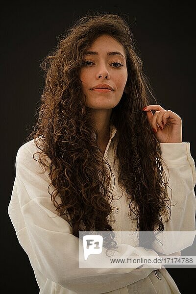 Studioporträt einer jungen Frau mit langen lockigen Haaren