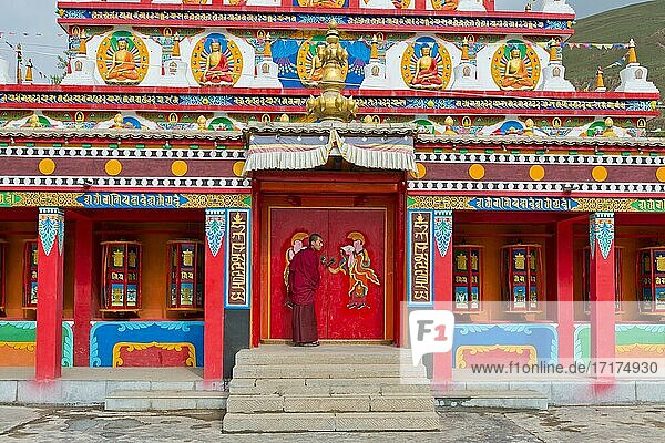 Tibetischer Buddhismus  tibetischer Mönch an neuer großer bemalter und vergoldeter Chörten  Stupa im Kloster Wutun Si  Tongren  Repkong  Qinghai  ehemals Amdo  Tibet  China  Asien