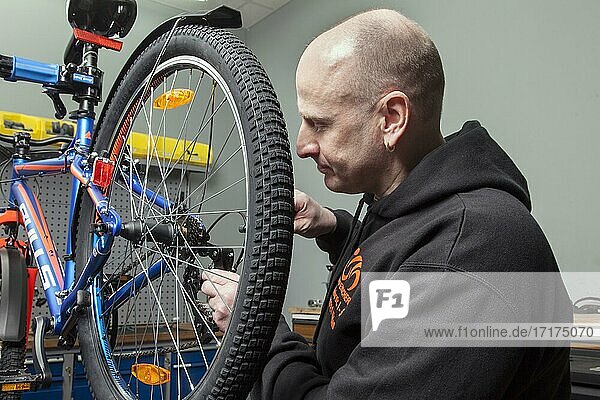 Bike mechanic in the bike workshop during an inspection on a mountain bike  checking and adjusting the gears
