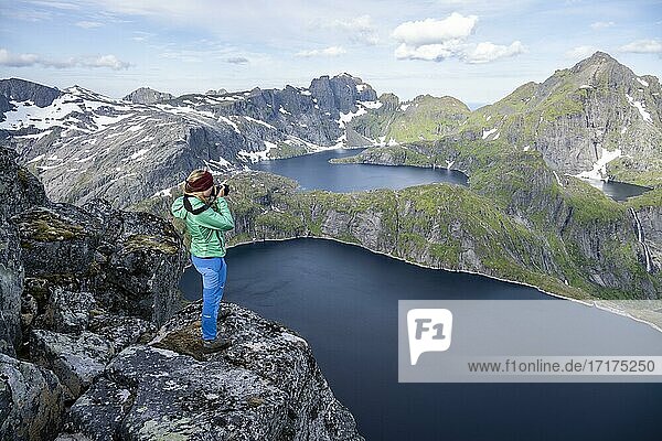 Junge Frau blickt über Berglandschaft mit See Tennesvatnet  Blick vom Gipfel des Munken  Moskenesöy  Lofoten  Nordland  Norwegen  Europa
