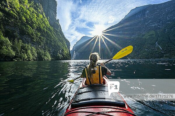 Junge Frau paddelt in einem Kajak  Geirangerfjord  bei Geiranger  Norwegen  Europa