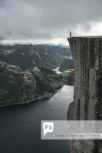 Person steht an steiler Klippe  Felskanzel Preikestolen  Lysefjord  Ryfylke  Rogaland  Norwegen  Europa