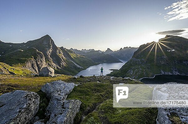 Young woman looking over fjord landscape  sun shining over mountain landscape with fjord Forsfjorden and lake Krokvatnet  Moskenesöy  Lofoten  Nordland  Norway  Europe