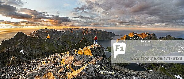 Hiker at the summit  evening mood  mountain landscape with Reinefjord and lake Krokvatnet  view from the summit of Hermannsdalstinden  Moskenesöy  Lofoten  Nordland  Norway  Europe