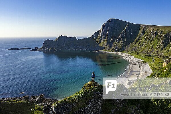 Hiker standing at the precipice  cliffs  beach and sea  in the back peak of the mountain Måtinden  near Stave  Nordland  Norway  Europe