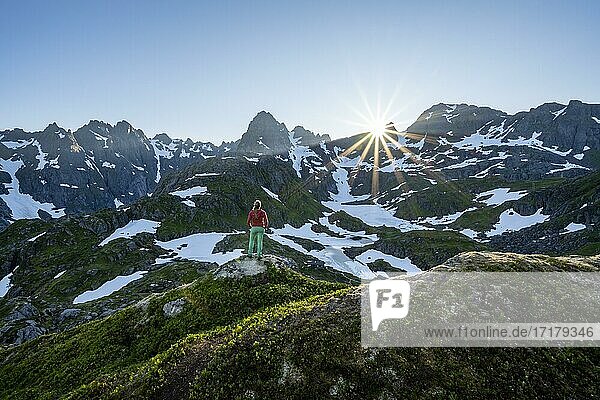 Junge Frau in den Bergen  genießt Ausblick  Berge und Schnee  Wanderung zur Trollfjord Hytta  am Trollfjord  Lofoten  Nordland  Norwegen  Europa