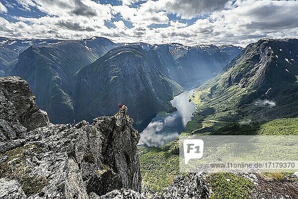 Wanderin steht auf Felszunge  Blick vom Gipfel des Breiskrednosi  Berge und Fjord  Nærøyfjord  Aurland  Norwegen  Europa