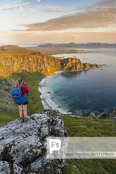 Wanderin steht auf einem Felsvorsprung mit Blick auf Strand und Meer  Gipfel des Berges Måtinden  bei Stave  Nordland  Norwegen  Europa