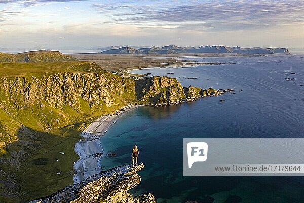 Evening atmosphere  hiker standing on a cliff  view to rocks  beach and sea  top of the mountain Måtinden  near Stave  Nordland  Norway  Europe