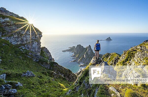 Evening sun  hiker standing on a rock  view of cliffs in the sea  top of the mountain Måtinden  near Stave  Nordland  Norway  Europe