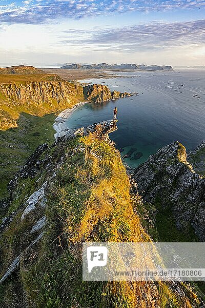 Evening atmosphere  hiker standing on a cliff  view to rocks  beach and sea  top of the mountain Måtinden  near Stave  Nordland  Norway  Europe
