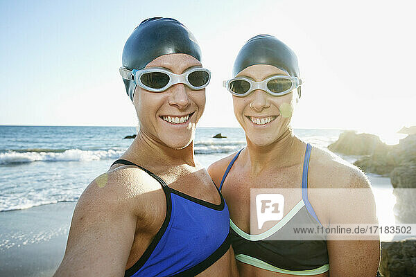 Zwei Schwestern  Triathletinnen im Training in Badebekleidung  Badehauben und Schwimmbrillen.
