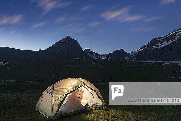 Silhouette of hiker inside the illuminated tent above lake Limmernsee at dusk  Canton of Glarus  Switzerland  Europe