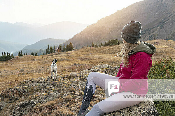 Frau zeltet mit Hund auf einem Berg im Urlaub