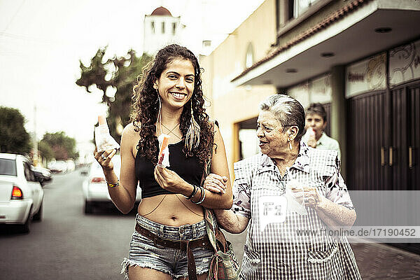 Junge attraktive Mexikanerin geht mit ihrer Großmutter über die örtliche Straße