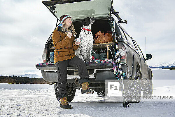 Frau mit Hund im Geländewagen im Winter