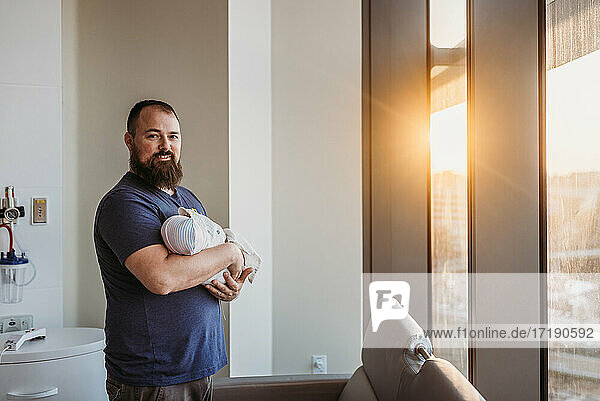 Ein neugeborener Junge wird von einem lächelnden Vater im Geburtshaus gehalten