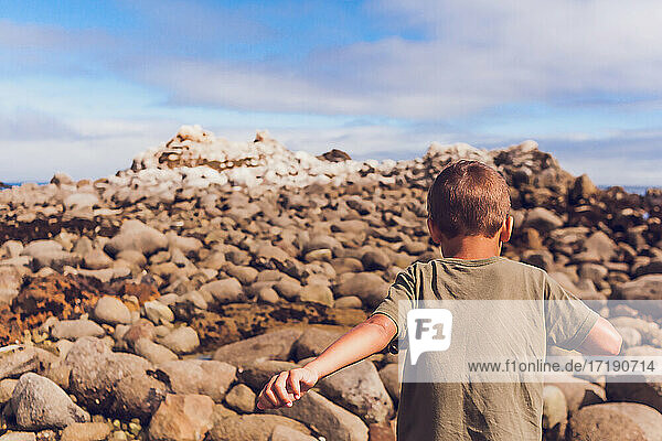Ein Junge klettert auf einen felsigen Berg - mit dem Rücken zur Kamera.