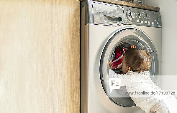 Kleines Mädchen schaut auf Waschmaschine