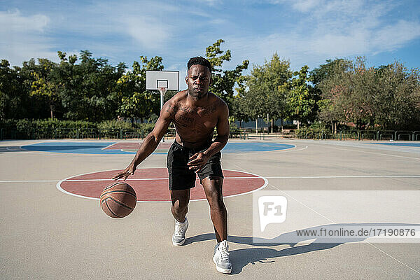 Schwarzer Basketballspieler ohne Hemd dribbelt Ball
