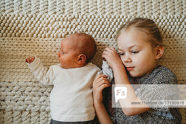Adorable weiße Schwester hält neugeborenes Baby die Hand zu Hause zeigt Liebe