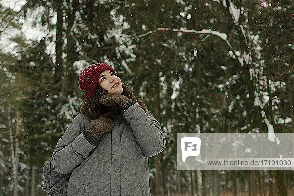 Ein Mädchen mit rotem Hut lächelt  schaut in den Himmel  lächelt  es schneit.