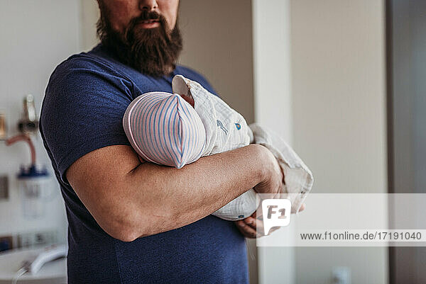 Newborn baby boy being held by father in birthing center