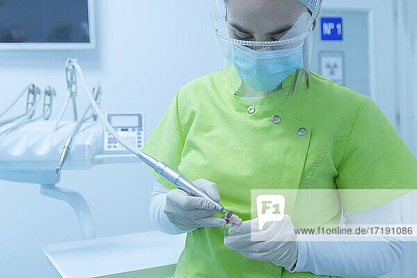 Zahnärztin in Schutzkleidung bei der Reinigung von Zahnersatz  Klinik