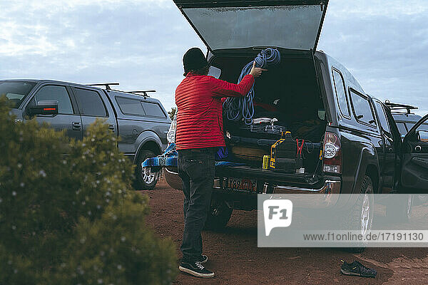 Mann bewahrt Seil im Kofferraum eines Geländewagens auf