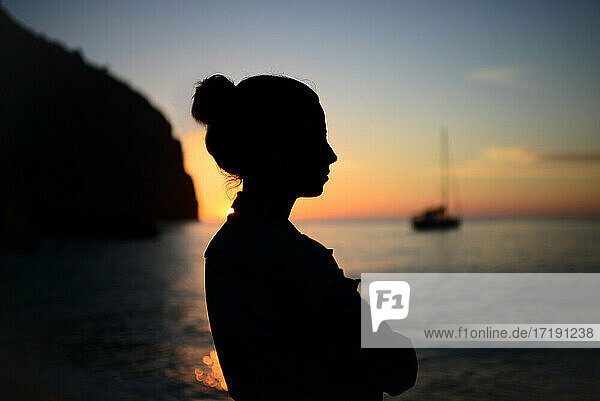 Silhouette einer nachdenklichen jungen Frau  die einen schönen Sonnenuntergang genießt