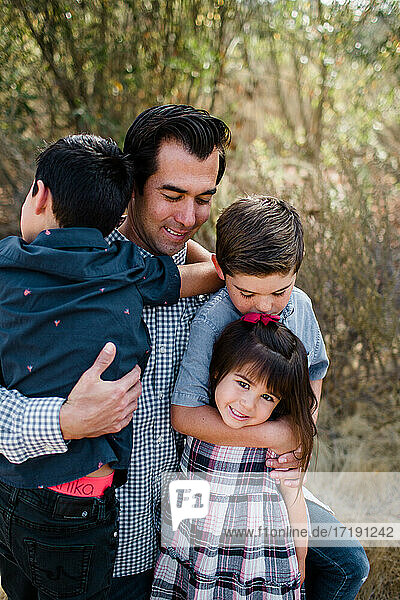 Vater hält drei Kinder auf einem Feld in San Diego