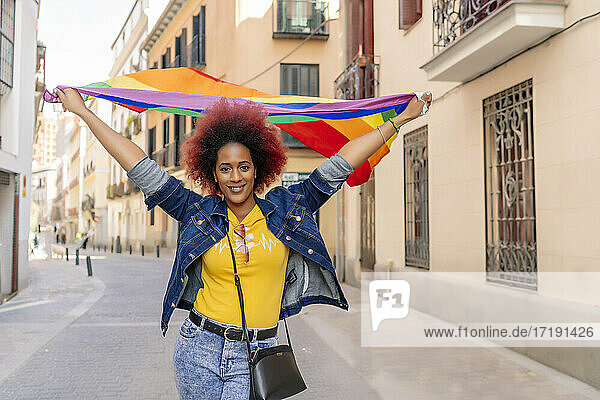 Frau mit Afro-Haar trägt Gay Pride Flagge