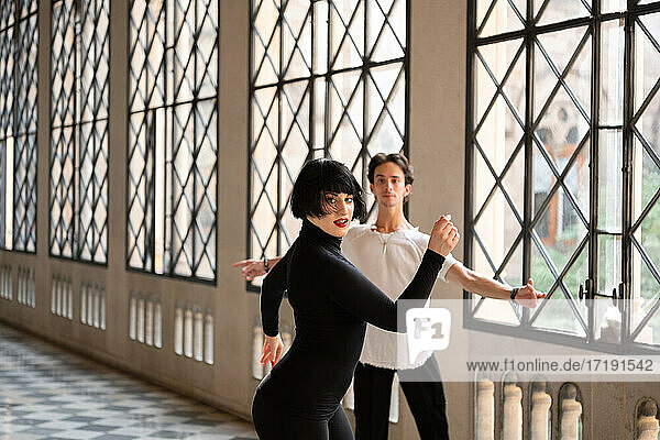 Anmutige Frau beim Üben eines lateinamerikanischen Tanzes mit Partner