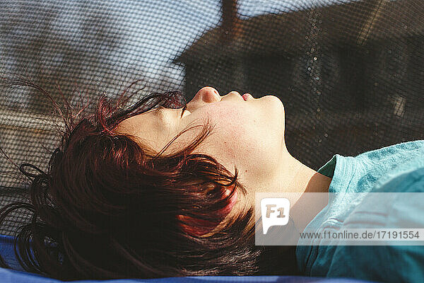Nahaufnahme eines Jungen auf einem Trampolin im warmen Sonnenschein