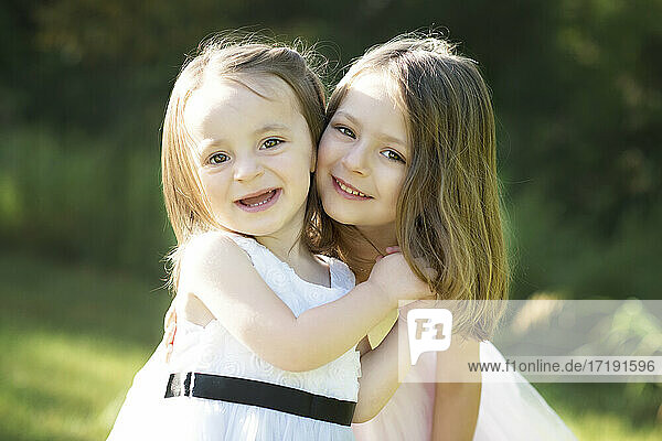 Zwei glückliche süße kleine Mädchen in Osterkleidern im Freien.