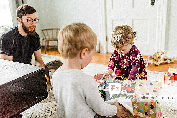Children unwrapping birthday presents in living room and being joyful