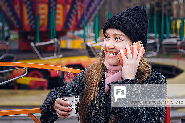 Mädchen mit Kaffee bei kaltem Wetter telefoniert im Park