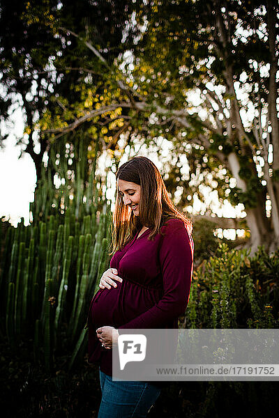 Schwangere Frau Mitte dreißig  stehend im Garten bei Sonnenuntergang in San Diego