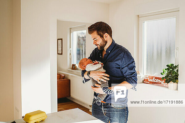 Glücklicher Vater hält sein neugeborenes Baby zu Hause während der Quarantäne