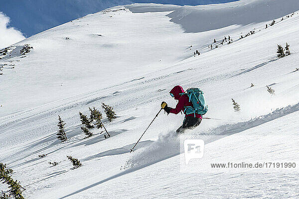 Frau mit Rucksack beim Skifahren auf einem schneebedeckten Berg im Urlaub