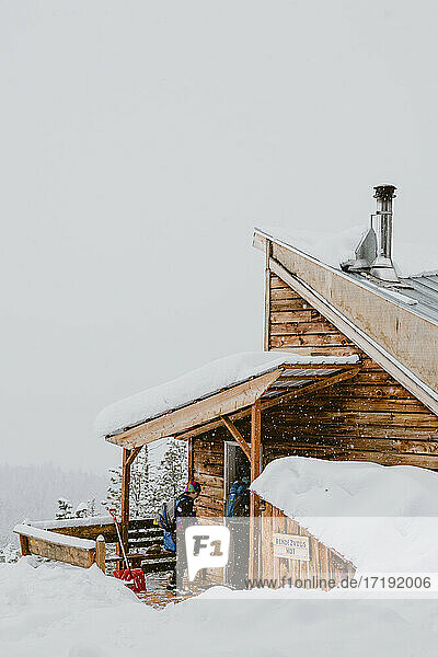 Zwei Freunde betreten eine rustikale Hütte  während es draußen schneit