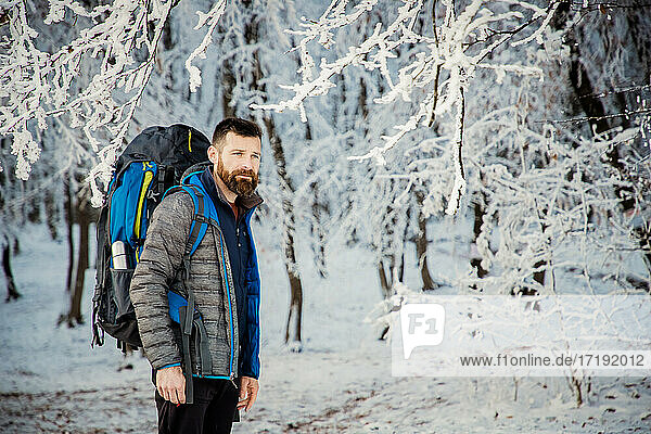 gutaussehender Mann beim Trekking in schöner Winterlandschaft soziale Dista
