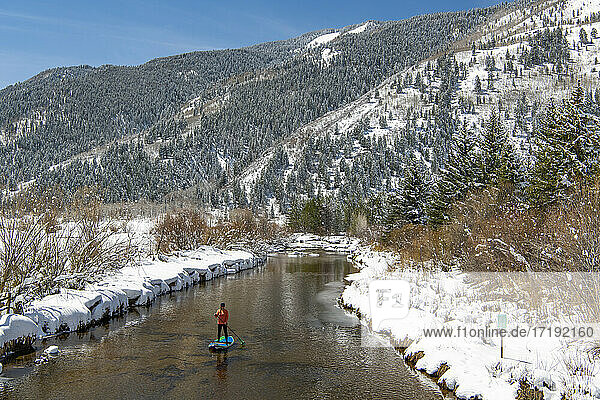 Frau paddelt im Winter auf einem Fluss