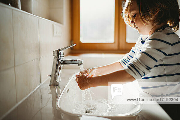 Seitenansicht eines jungen Kindes im Vorschulalter  das sich die Hände mit Seife wäscht