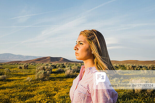 sunlit profile of young woman in desert flower field