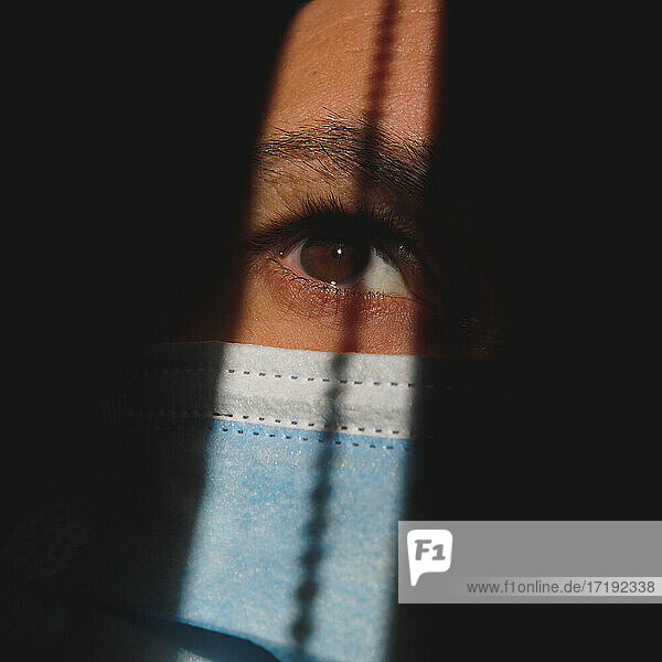 Mann mit Maske im Schatten  der das braune Auge zeigt