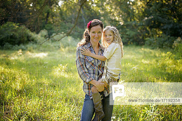 Mother holding little blond girl in a meadow in the country.